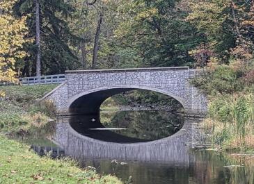 Historic footbridge reflecting on the water at Akron Falls Park